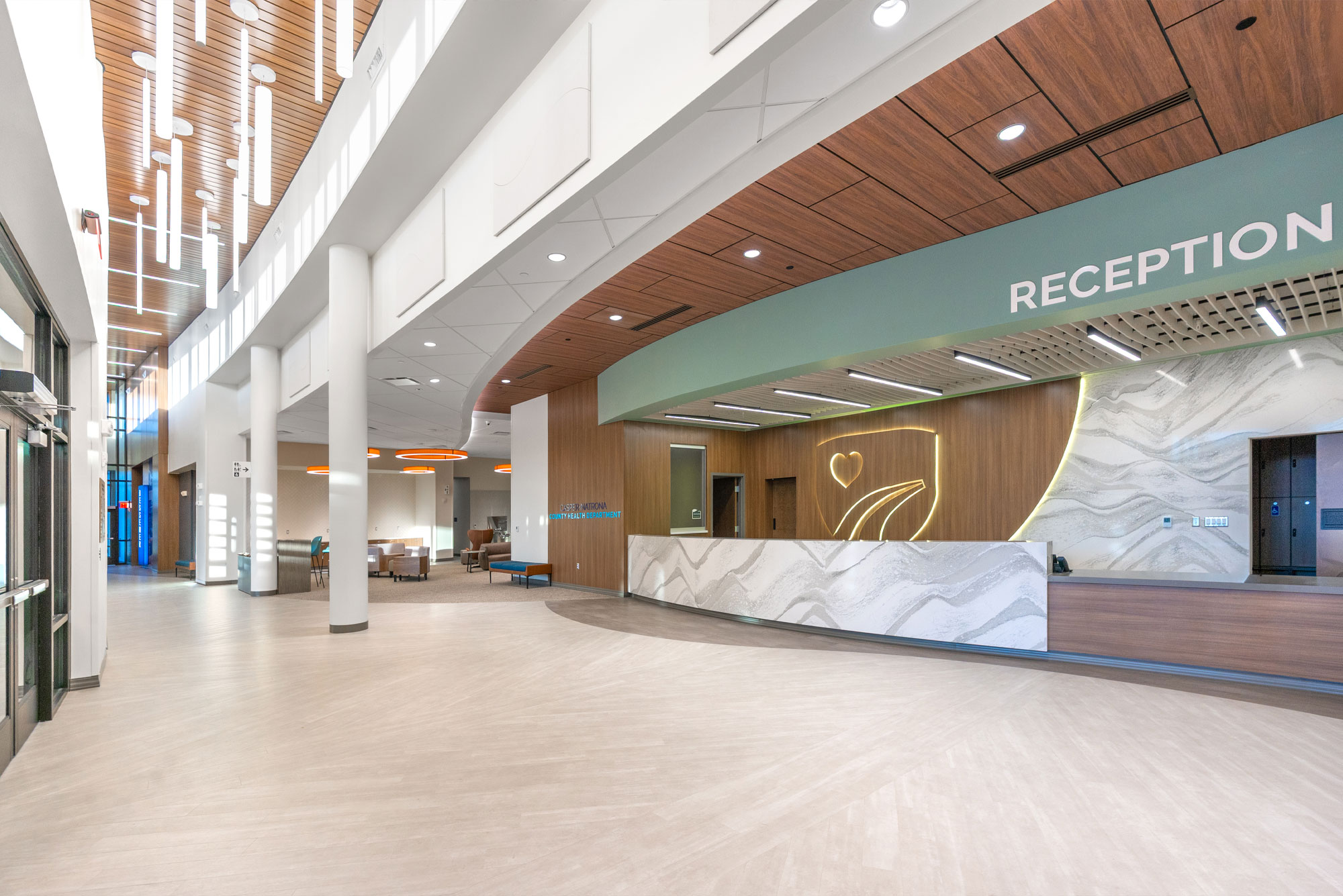 Casper-Natrona County Health Department reception lobby with a curved marble desk, glowing heart motif, and warm wood ceiling panels.